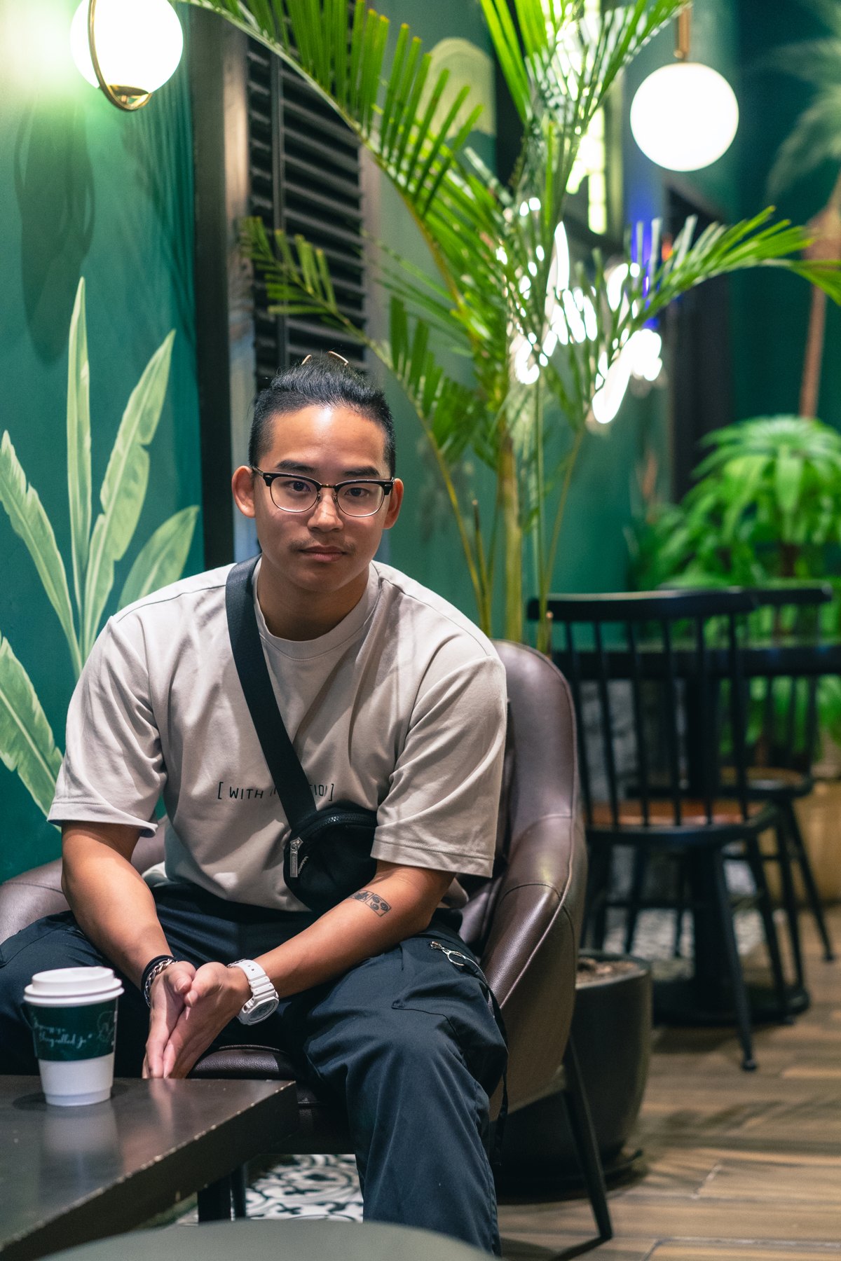 Calvin sitting in a café chair with a coffee, looking at the camera